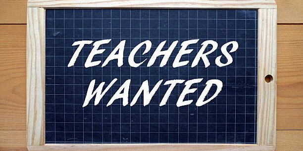 The phrase Teachers Wanted in white text on a slate blackboard